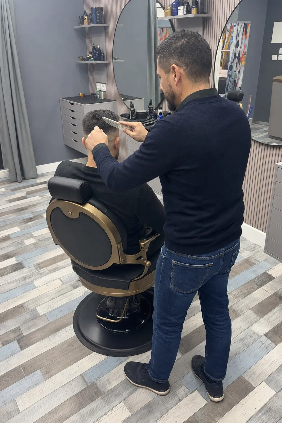 Le barbier coiffant et finissant la coupe d'un client